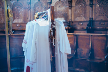hangers with clothes of altar boys and wooden crosses, in the church