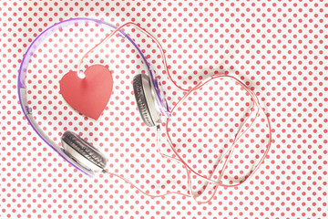 Love music concept with headphones and a red heart on a vintage dot pattern background. Table top view
