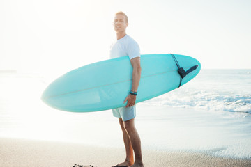 Portrait of surfer standing with surfboard near the ocean