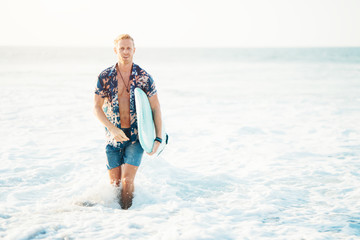 Man surfer walking with surfboard out of the water