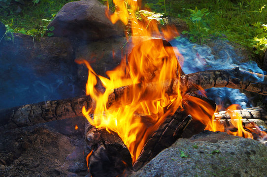 bonfire between boulders against the background of green grass