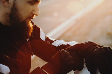 Close up portrait of a confident bearded bike adventurer traveling on his bike and looking on his smartwatch to see tha map.