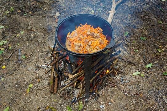 meat with carrot in a cauldron over a fire