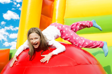 Happy little girl having lots of fun on a inflate castle while jumping.
