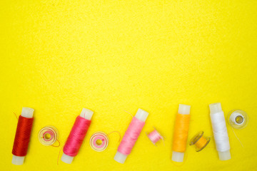 Multicolored thread coils red pink yellow white on yellow background