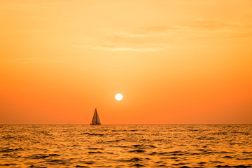 yacht at sea on the horizon at sunset and orange sky