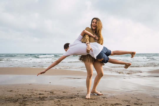 girl holding her friend on beach and having fun