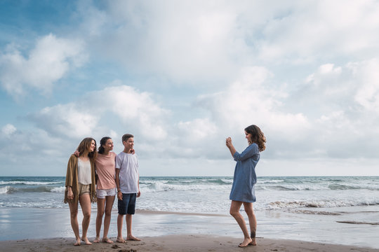 Mother taking picture of her children on beach