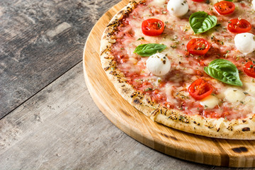 Pizza with tomatoes, cheese and basil on wooden table. Copyspace