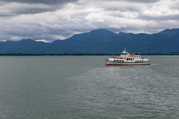 Single boat on a big lake in front of mountains in bavaria under cloudy sky