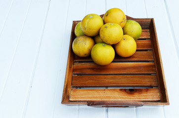 Orange fruits in wooden basket on white table with vertical side veiws