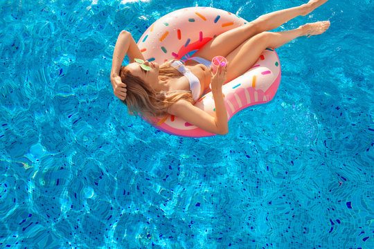 Summer Vacation. Woman in bikini on the inflatable donut mattress in the SPA swimming pool. Beach at the blue sea.