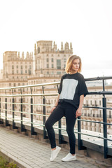 beautiful young blonde girl on the city background during sunset