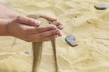 Female hands with sand on the beach.