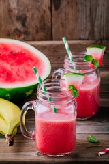Watermelon and banana  smoothie in mason jars with mint on wooden background