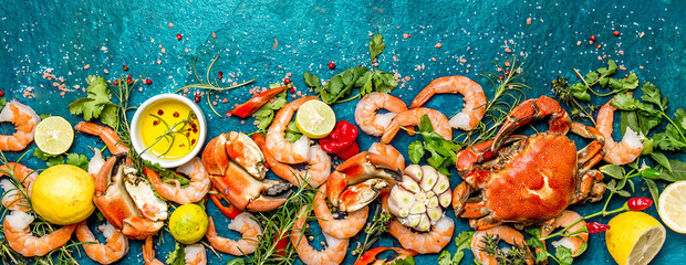 Baner. Fresh raw seafood - shrimps and crabs with herbs and spices on turquoise background. Copy space