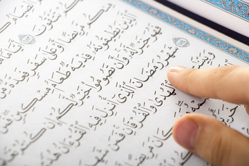 Muslim boy pointing to the word : Ramadan ( The holy Month ) while reading the Quraan in a mosque