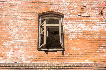 Old red brick wall with destroyed window.