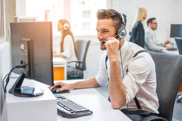 Side view of beautiful handsome operator man agent with headset working in call centre 