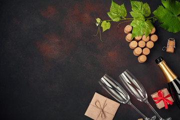 Bottle of champagne, grape bunch of cork with leaves, gift box on rusty background