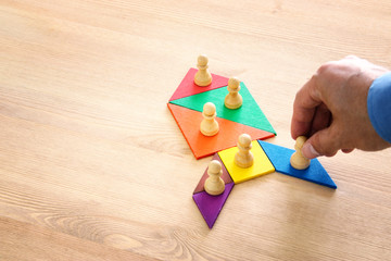 image of tangram puzzle blocks with chess figures over wooden table ,human resources and management...