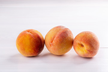 Ripe peaches close-up on a white wooden background.