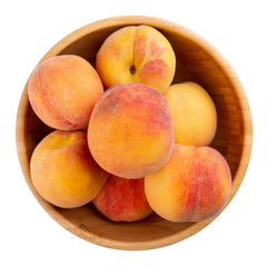 Ripe peaches in wooden bowl isolated on white. Top view.