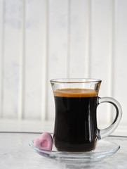 Espresso. Glass cup of espresso with sugar in the form of heart on a light background