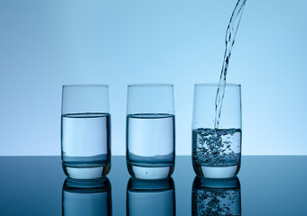 Creative splashing water in the glass on blue background.