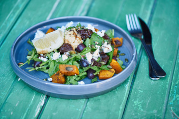 Salad sitting with cutlery on a rustic turquoise wooden table