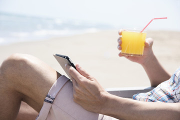 man using a tablet on the beach
