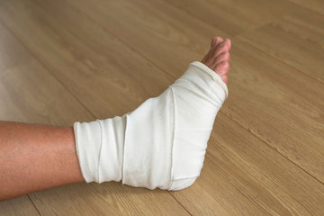 Injured male leg, cruciform bandage on the ankle joint.