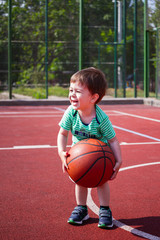 a boy of two years playing with a ball on the basketball court. Toddler boy playing basketball