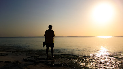 The photographer on the shore of the ocean watching the sunset