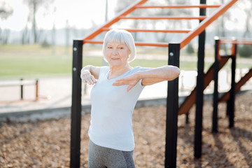 Feeling good. Inspired blond woman smiling and exercising in the open air