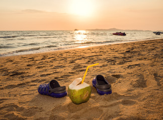 Coconut and slippers on the beach. Sunset on the beach.