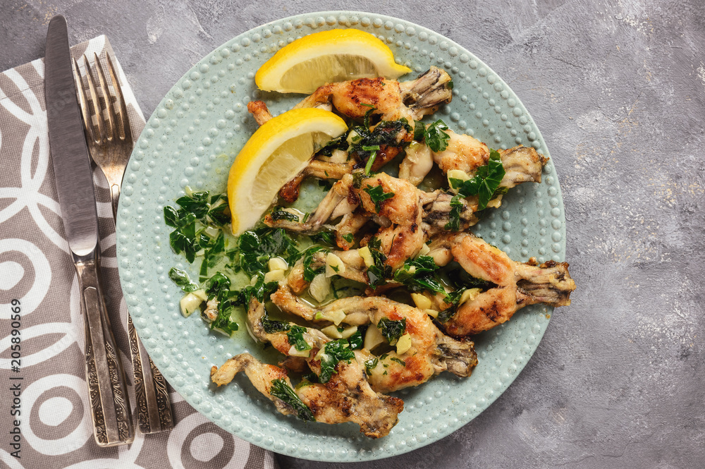 Wall mural Frog legs baked with garlic butter and parsley.