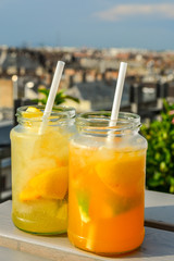 Lemonade cocktails with lemon in glass jar, cold refreshing drink or beverage with ice at a rooftop bar.