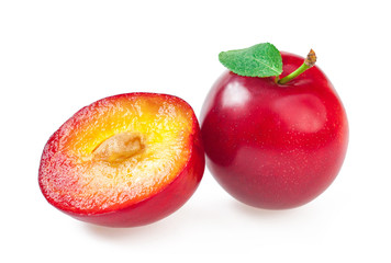 Ripe delicious plums with leaves, and a juicy plum cut into a half. Closeup, isolated on white
