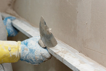 The process of leveling raw plaster on the wall using a board.