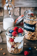 Healthy blueberry and raspberry parfait with greek yogurt in glass mason jar on wood background
