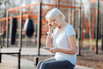 I love music. Concentrated thin woman listening to music while relaxing on the bench
