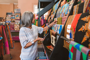 Mature woman looking at colorful fabric in her shop