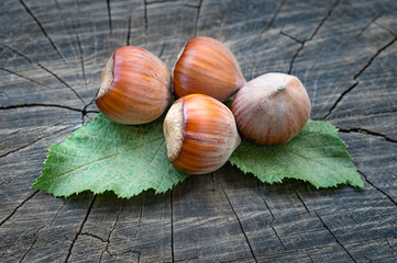 hazel nuts with leaves on old wooden background, close-up view