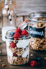 Healthy blueberry and raspberry parfait with greek yogurt in glass mason jar on wood background