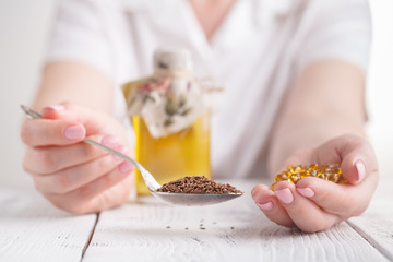 Flax seeds capsules and oil in bottle on wooden background