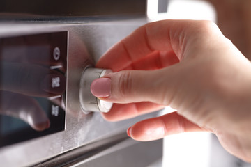 Woman Using Microwave Oven For Baking Fresh Cookies In Kitchen