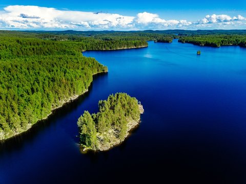 Aerial view of blue lake and green forest. Beautiful summer landscape in Finland.