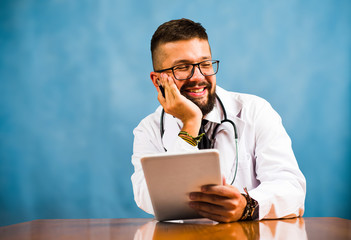 Male doctor holding tablet in office desk