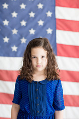 Little girl standing in front of an American flag background